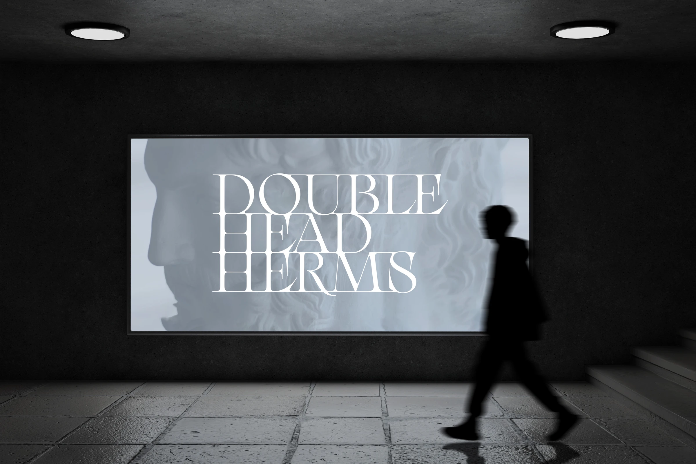 Double Head Herms title projected on a screen in a dark underpass, a person walking past