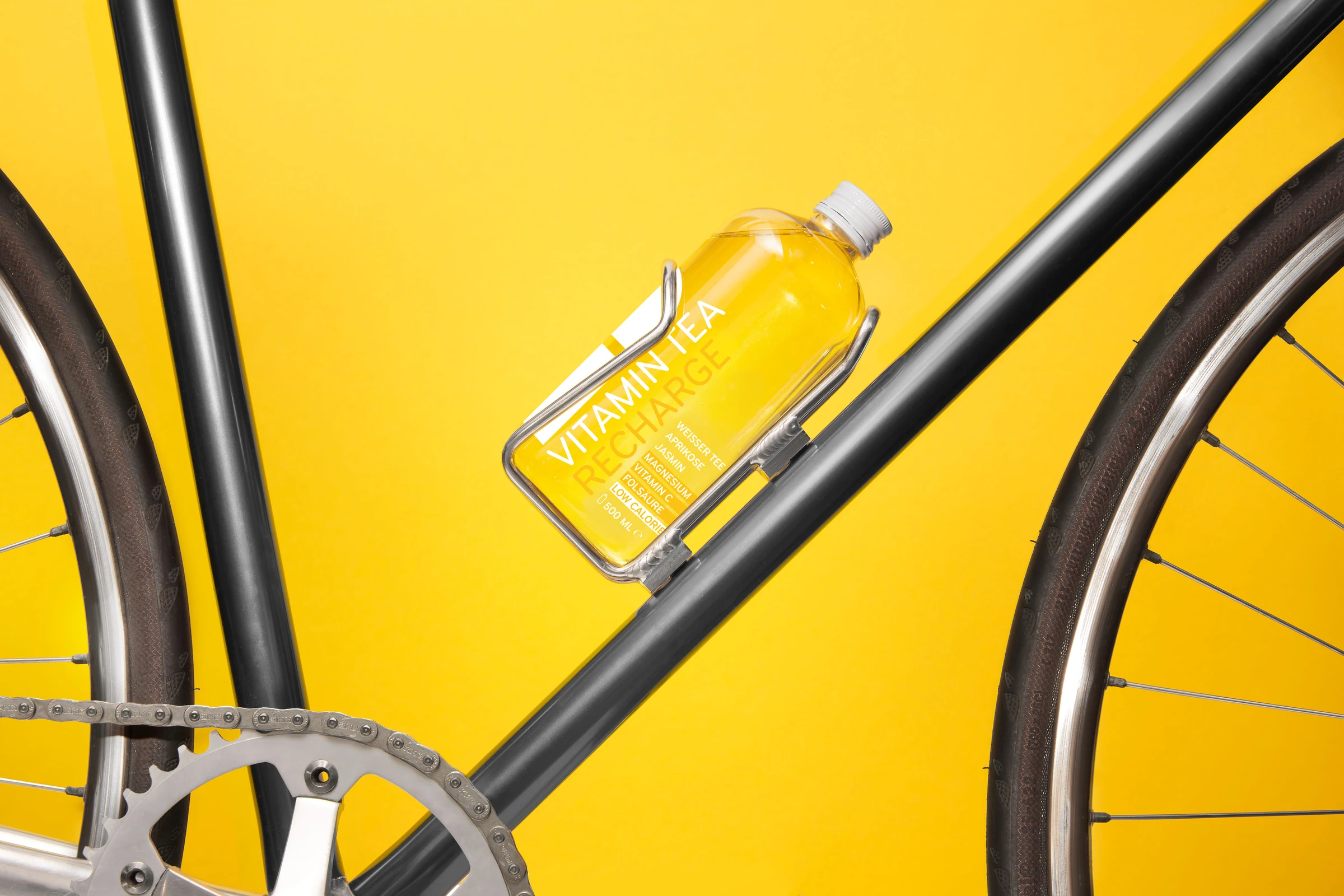 Vitamin Tea bottle in a holder on a bicycle, against a yellow background