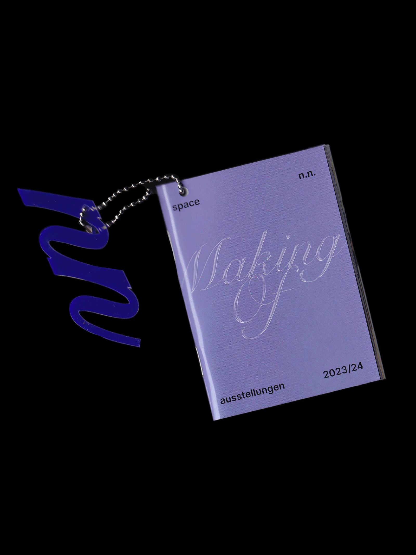 Making-of booklet with a calligraphic cover, hanging from a chain with an n.n. pendant