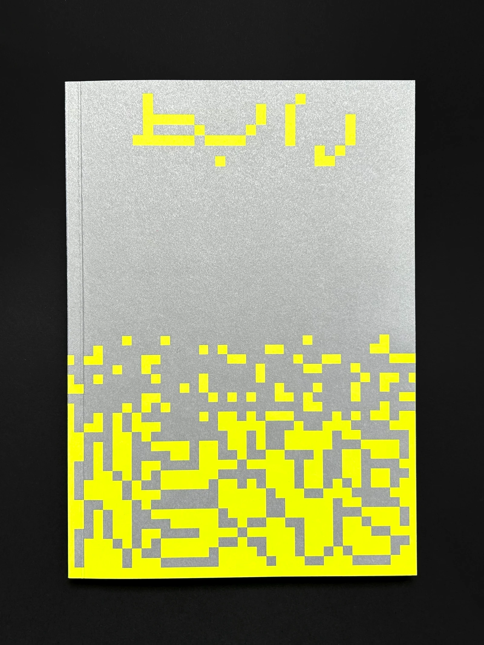 Silver catalog cover with neon yellow pixel lettering