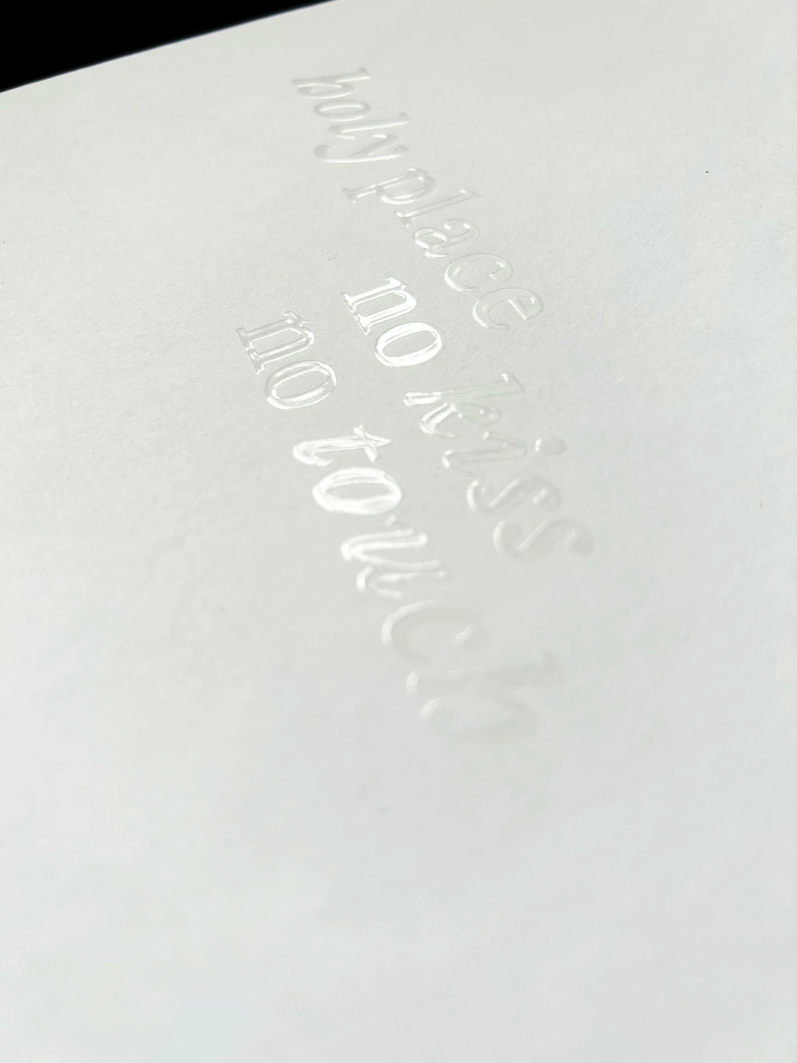 Close-up of the white cover with lettering in transparent relief varnish