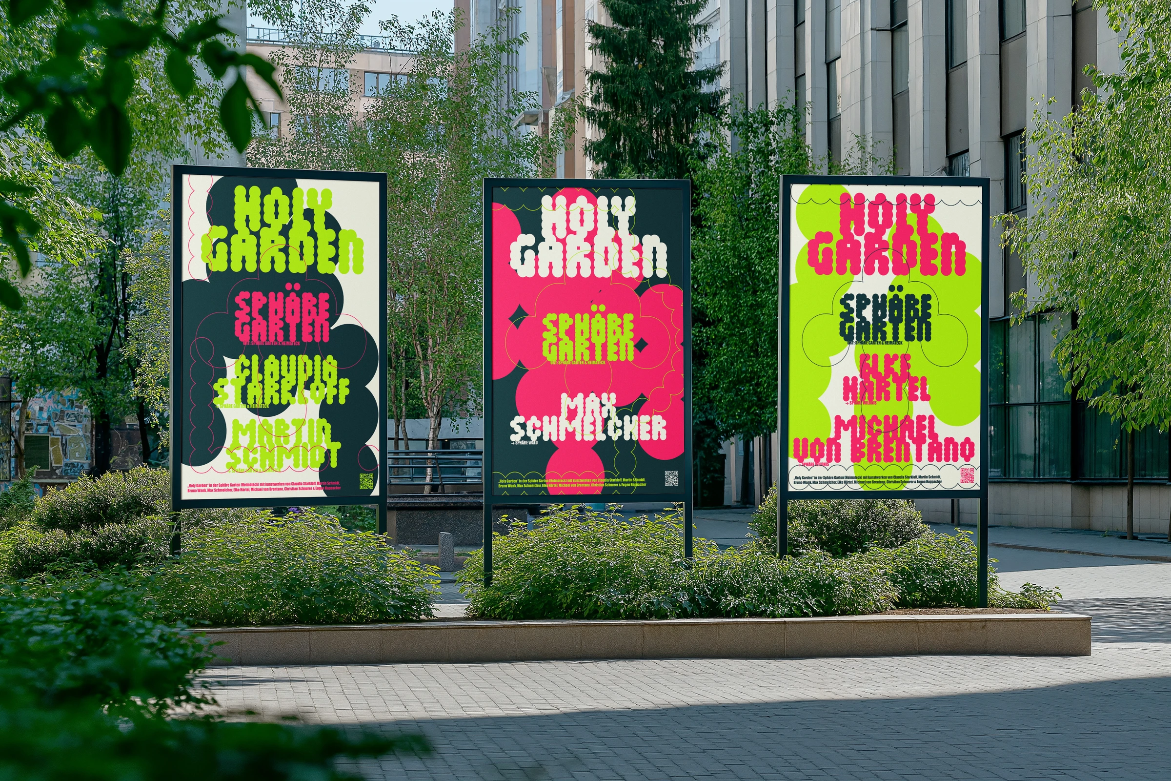 Three Holy Garden posters in pink and green on display stands in a park