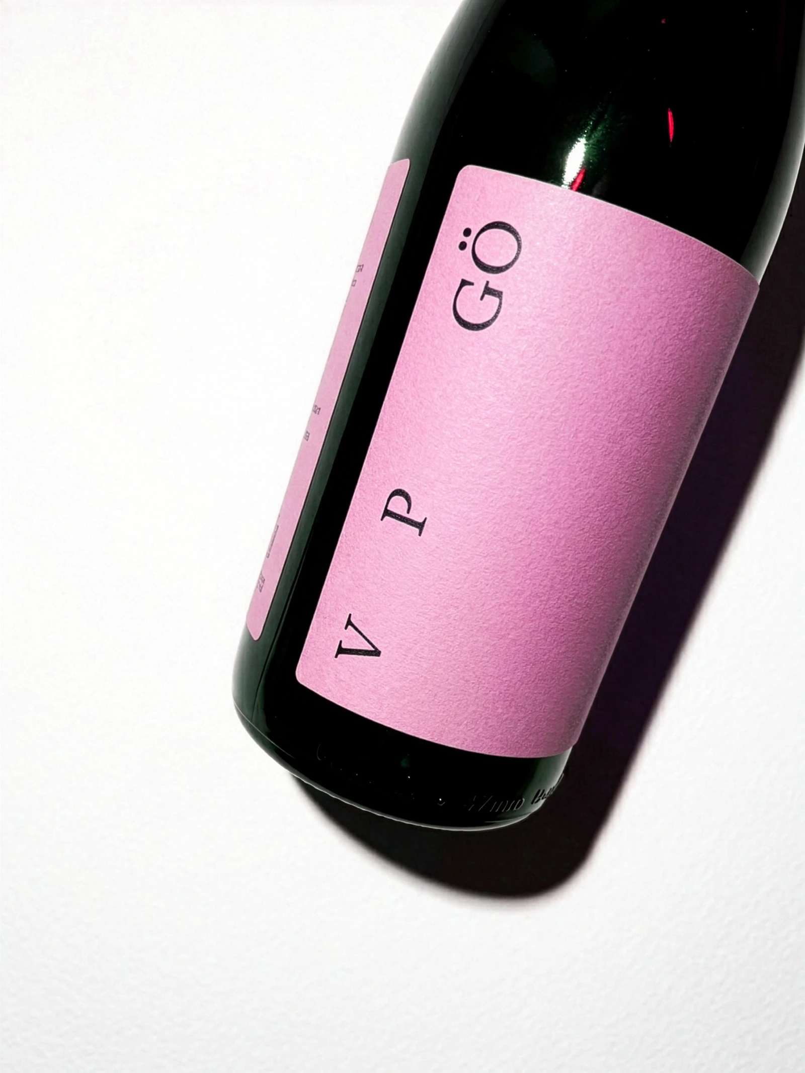 Wankwein bottle with a pink label reading V P GÖ, lying on a white surface