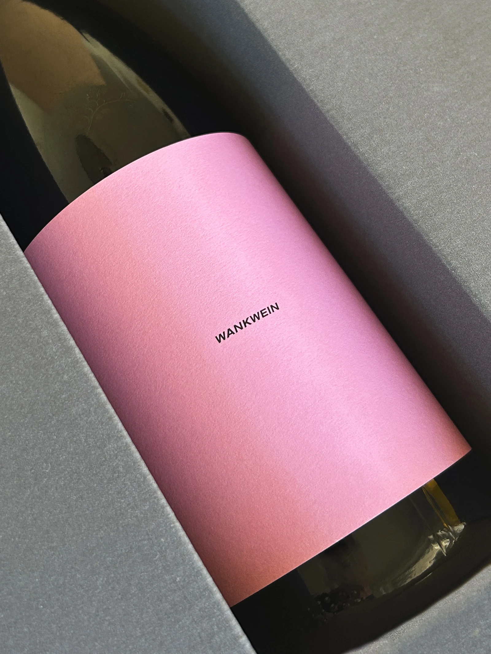 Close-up of the pink Wankwein label on a bottle in a grey box