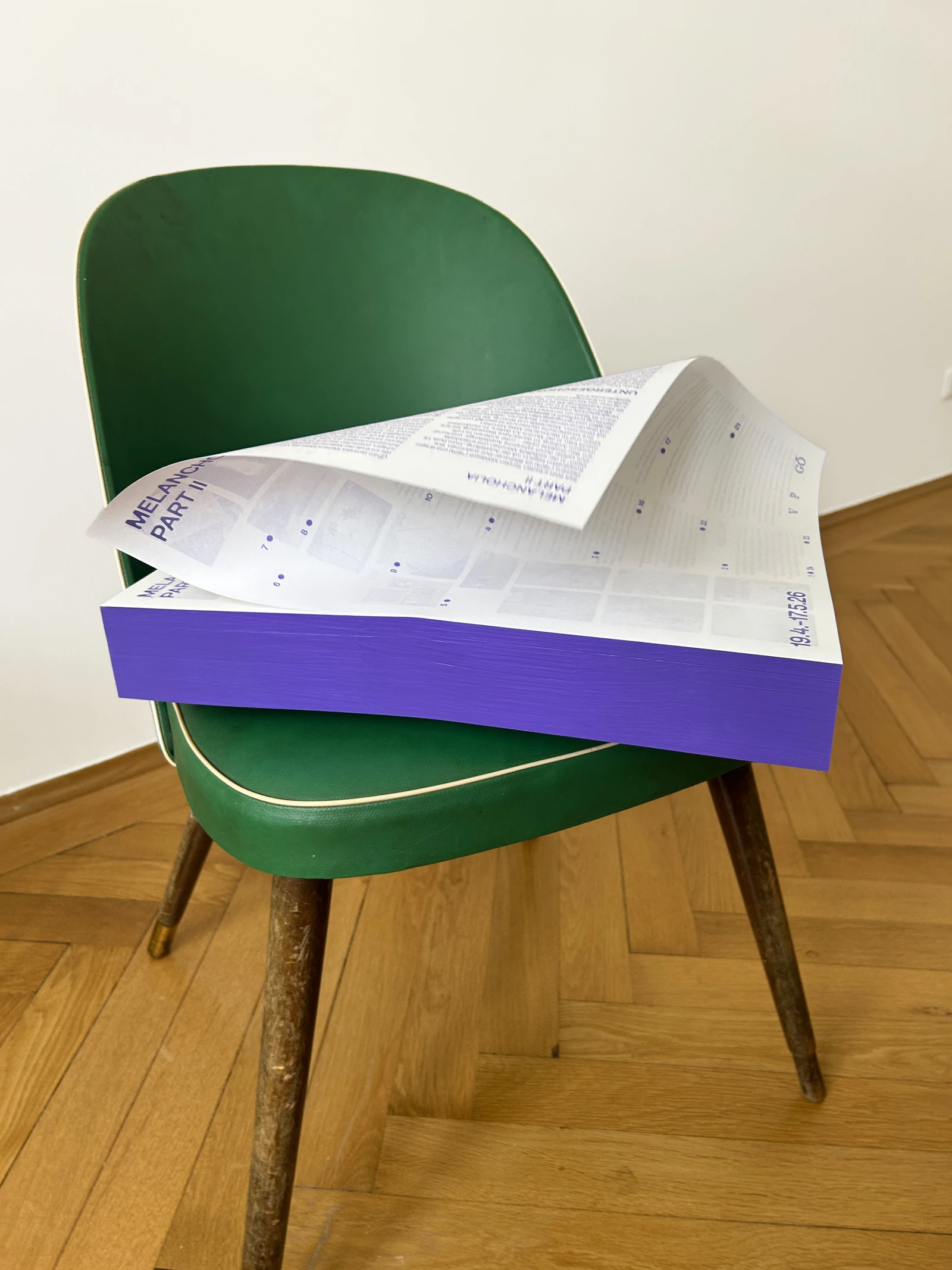 Stack of paint-by-numbers sheets with a purple edge on a green chair