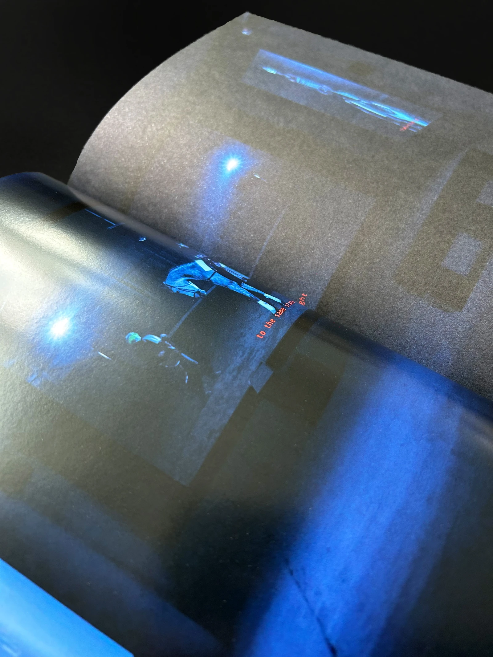 Curving catalog page with a blue-lit installation photo, showing the change from coated to uncoated paper