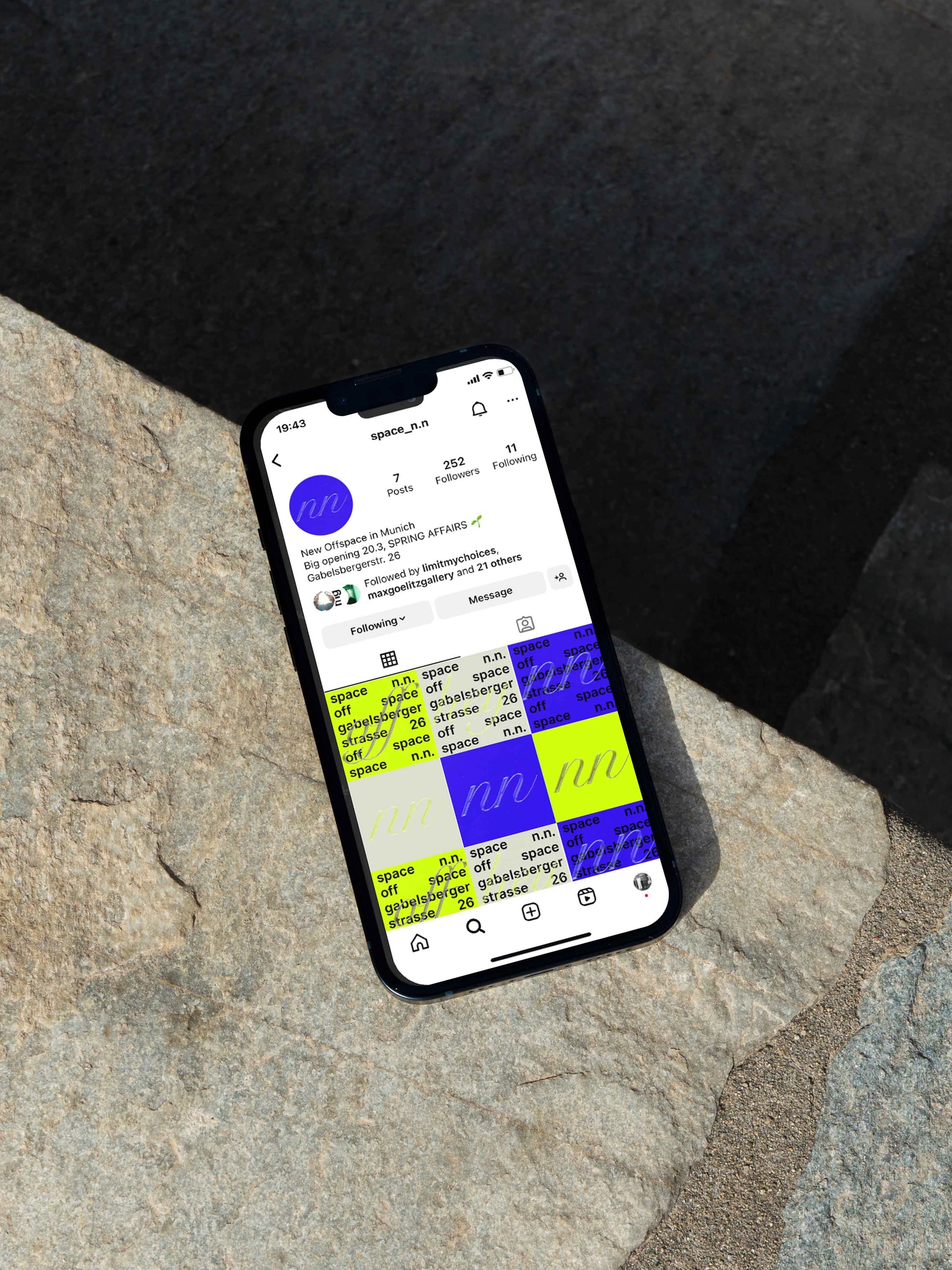 Smartphone showing the space n.n. Instagram feed, lying on a stone