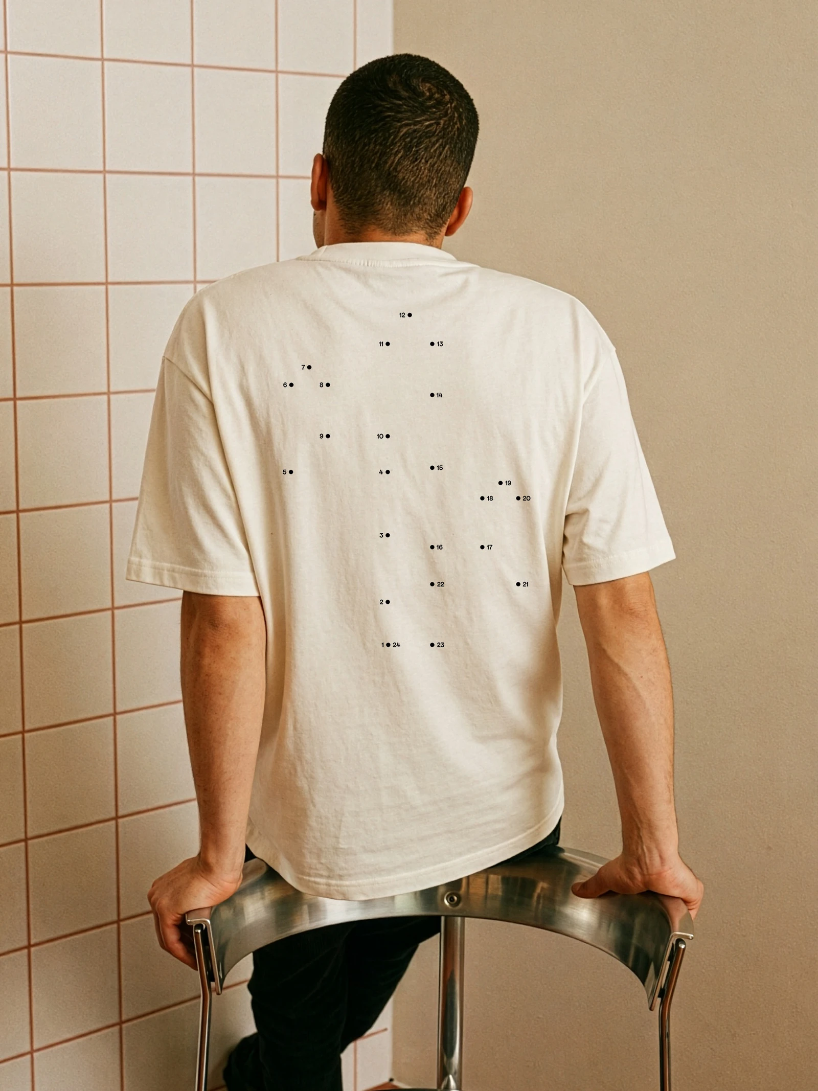 Man seen from behind in a white T-shirt with a numbered dot pattern