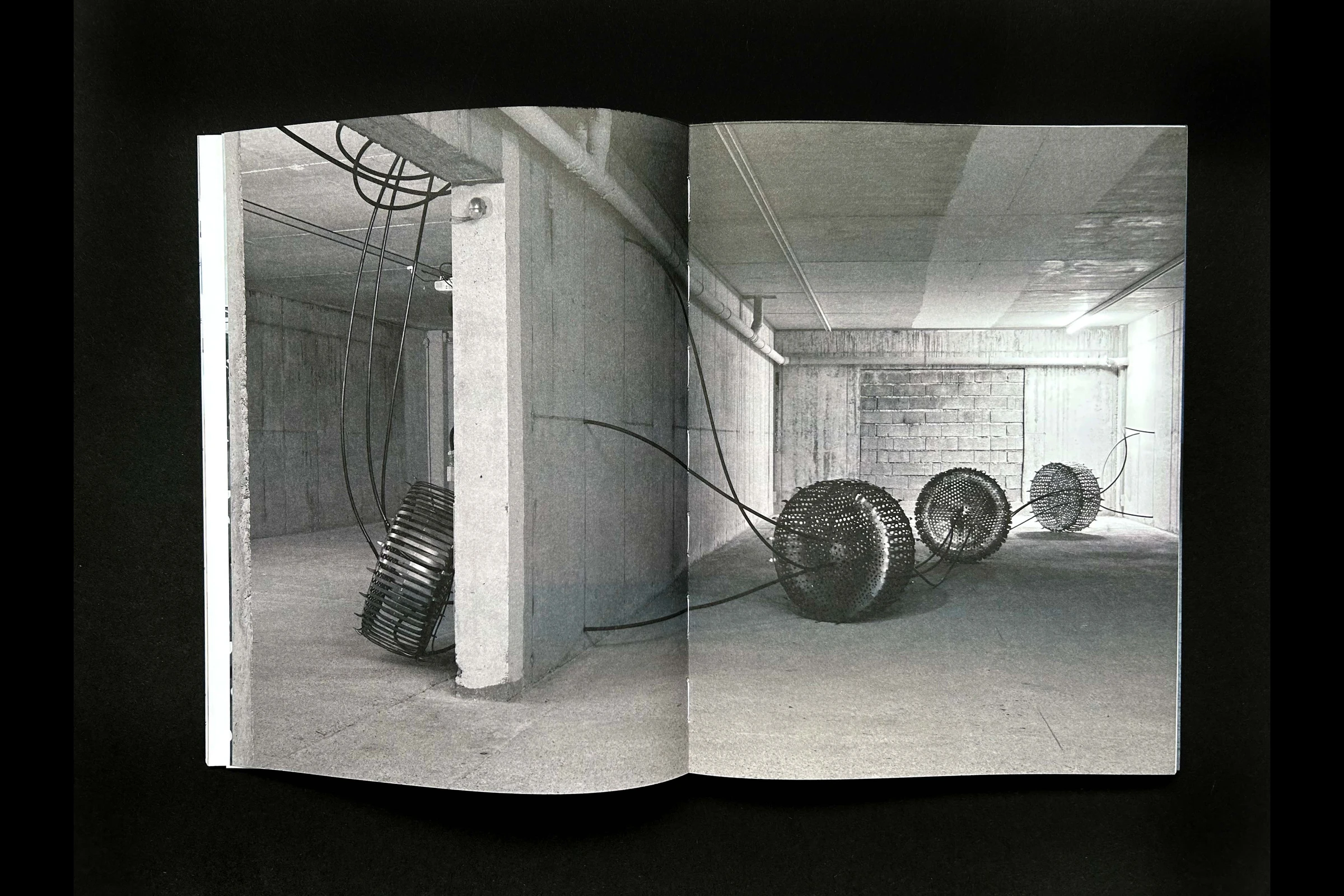 Catalog spread with black-and-white photos of tyre sculptures in a concrete room